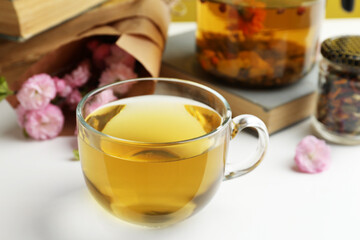 Glass cup of freshly brewed tea and flowers on light table