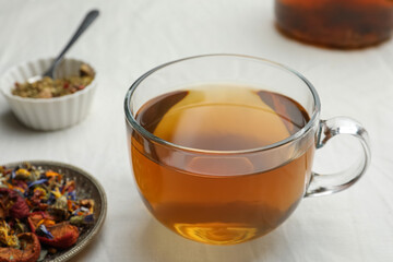 Cup of freshly brewed tea, dried herbs and berries on white table