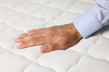 Man touching soft white mattress, closeup view