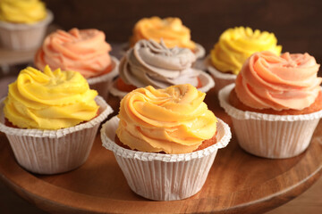 Obraz na płótnie Canvas Tasty cupcakes with cream on wooden stand, closeup