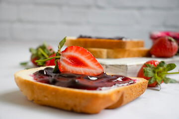 Bread, fresh strawberry, jam on wooden background