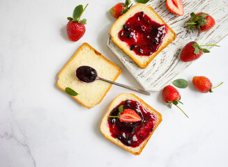 Bread, fresh strawberry, jam on wooden background