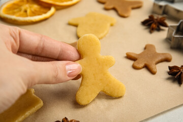 Fototapeta na wymiar Woman holding uncooked cookie at table, closeup. Christmas biscuits