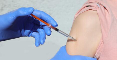 arm of young student during vaccination against virus and doctor's hands