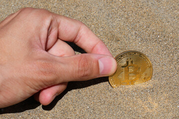 hand picking up a coin with the capital letter B symbolizing the mined BITCOIN