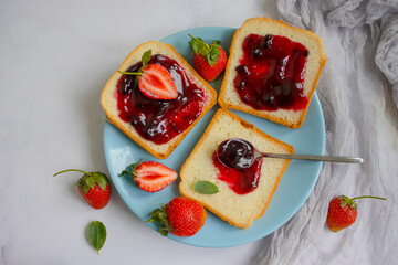 Bread, fresh strawberry, jam on wooden background