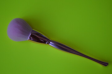 Professional cosmetic makeup brush on a green background for applying powder, shadows and blush and other cosmetic products