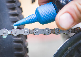 Senior man hands spraying an oil to chain from the wheel bike, doing maintenance