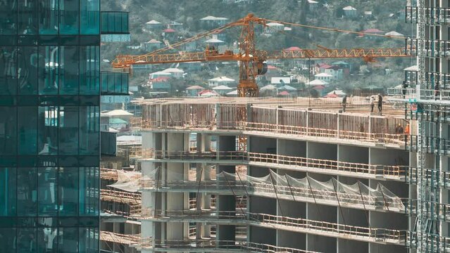 Workers work in a construction cradle, on scaffolding during the construction of a high-rise building. timelapse time lapse development on construction site. Construction And Development Of Modern