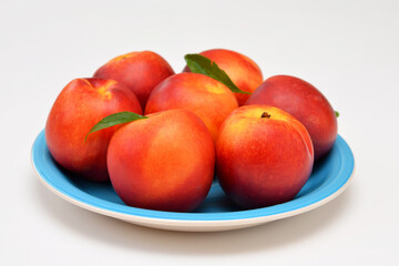 ripe nectarines plate with peaches on white background close-up