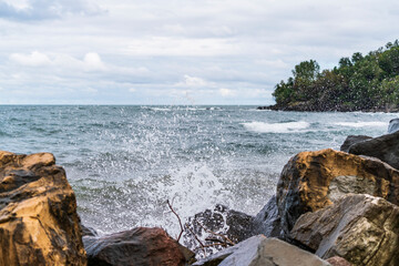 Fototapeta na wymiar Rough waves that break with the stones on the sea shore