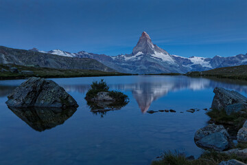 Fototapeta na wymiar Blue night on Matterhorn summit reflecting on a mountain lake.