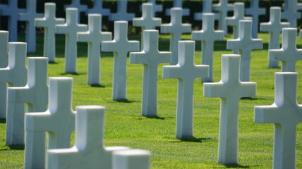 white crosses in a perspective row of an American cemetery with an English lawn