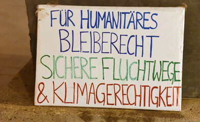 Pappschild auf einer Demo: "Für humanitäres Bleiberecht, sichere Fluchtwege und Klimagerechtigkeit"