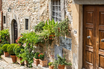 Fototapeta na wymiar Picturesque view on ancient light stone building. Lots of flower pots beside building wall and secured on the ancient stone wall. 