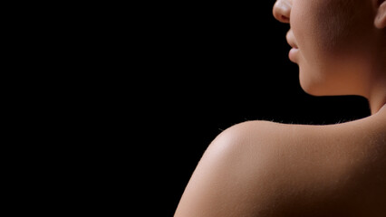 Big close-up shot of nude shoulder of gorgeous slim young white-skinned woman on black background | Body hydration concept