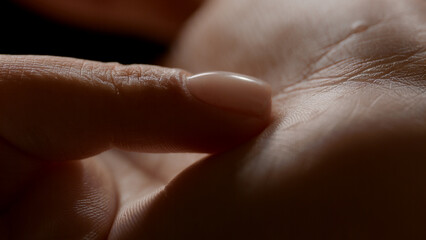 Macro shot of woman's finger touches her soft clean palm on black background | Skin texture shot for skin nutrition concept