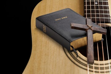 Holy Bible with acoustic guitar and religious crucifix cross on desk, gospel music concept