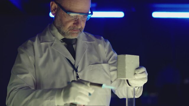 Professional tester testing , burning piece of fireproof building material  by gas torch inside  futuristic laboratory.  Construction engineer doing experiment . Physicist working in lab . Slow motion
