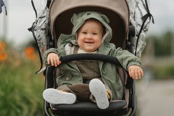 A female toddler is smiling in her stroller on a cloudy day. A young girl rejoices in a baby...