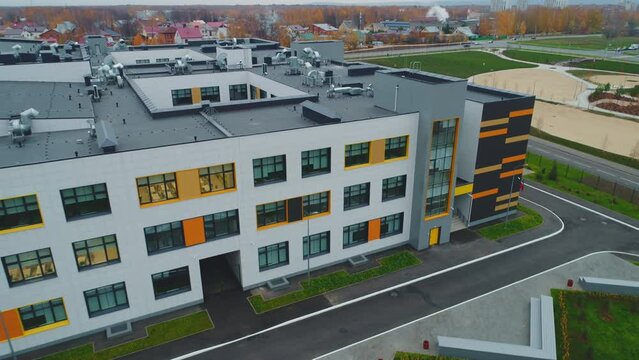Large school building with flat roof and large windows on city street bird eye view. Contemporary urban architecture