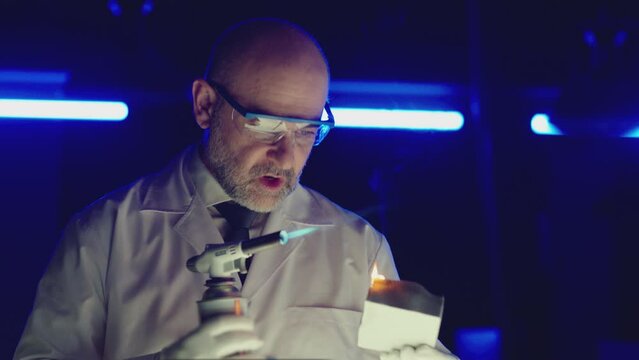 Professional tester testing , burning piece of fireproof building material by gas torch inside futuristic laboratory. Construction engineer doing experiment . Physicist working in lab . Slow motion