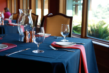 Table setting in  a restaurant with a blue tablecloth and red napkins