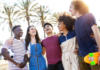 Group of five happy young people standing outside together on vacation - Multiracial friends enjoying summertime on holidays