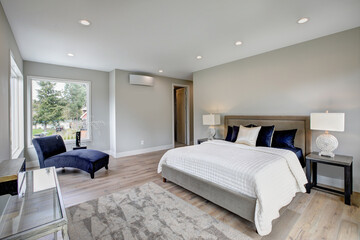 Bed with blue and white bedding and natural luxury tones lamps, wall and bed frame. Design details...