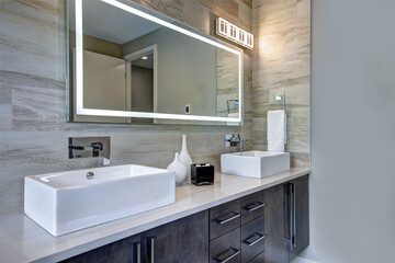 Contemporary bathroom interior with beige ceramic tiles, luxury details, huge light up mirror and...