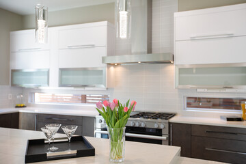 Luxury white and brown modern kitchen in a brand new home with tulip flowers. 