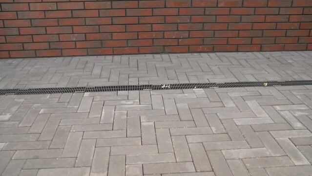 Gray paving stones and the facade of the house. Weathered brick fa ade with stone pavement. Gray stone blocks freshly laid.