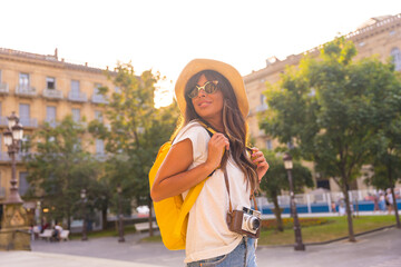 Portrait of a tourist in a travel hat at sunset, photo camera in the city in summer