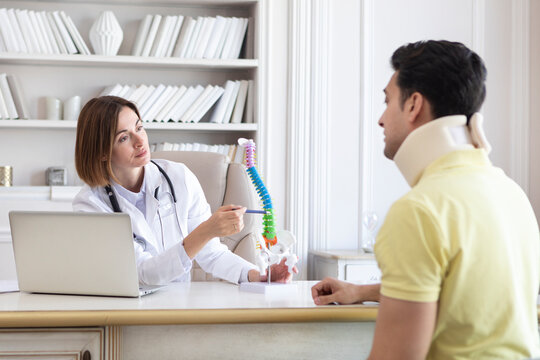 Female doctor orthopedist explaining to her patient with serious neck injury in neck brace about importance of cervical collar for healthy cure - Powered by Adobe