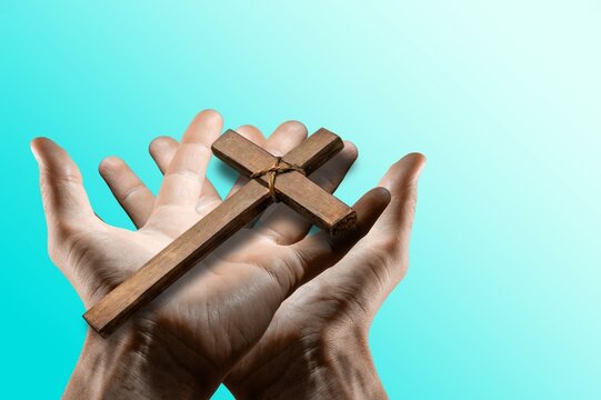 Human hand holding wooden cross crucifix. Catholicism, Christianity, Thanksgiving, Catholic and Christian faith concept.