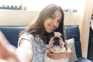 Young latin woman takes a selfie with her dog (french bulldog)