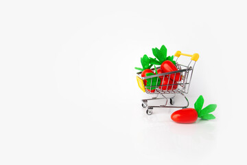 toy carrots in a small supermarket shopping cart, harvest, carotene, vitamins, vegetables, vegetarian diet, eco-friendly toys, farm products, white background, space for text, healthy lifestyle