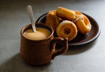 The most delicious homemade donuts and coffee with milk in a folk mug. Home cooking.