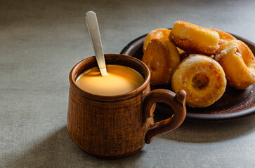 The most delicious homemade donuts and coffee with milk in a folk mug. Home cooking.