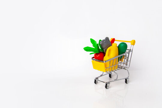 toy shopping cart full of plastic products for children's educational game of shopping, montessori, toy food, white background, space for text, useful skills for preschoolers, humanitarian aid