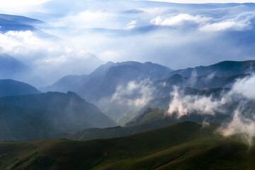 evening mountain landscape with sun rays and clouds, green alpine meadows, tourism, travel, tranquility, harmony, beauty of the planet earth, ecology day, space for text, sky before a thunderstorm