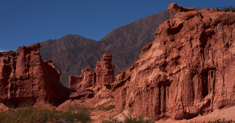 rock formation of reddish tones with mountains in the background of South America