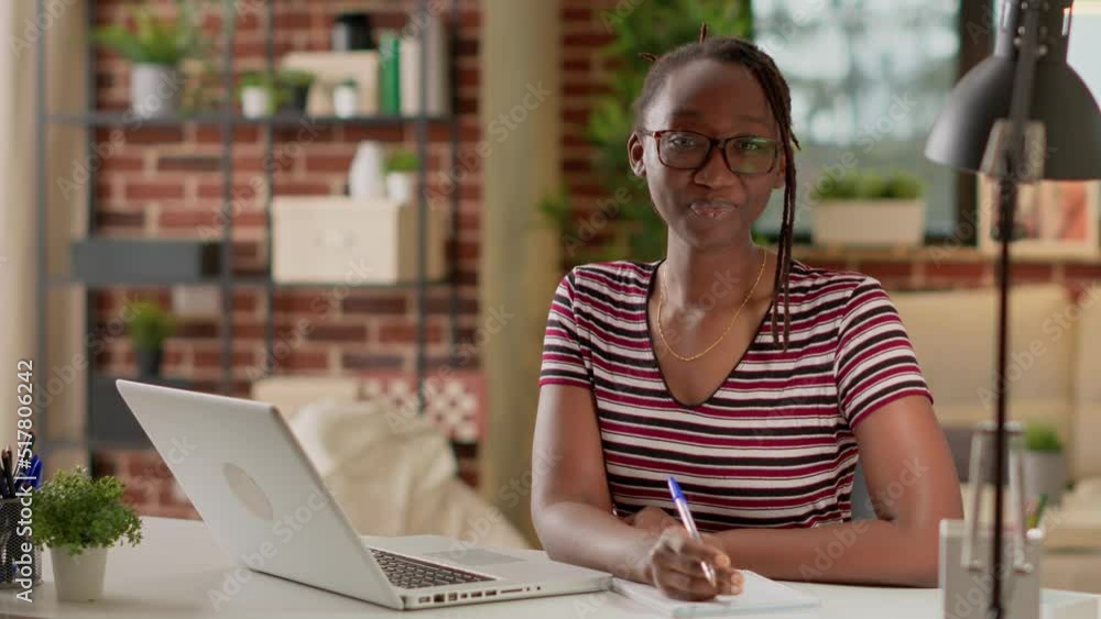 Poster portrait of freelancer taking notes at remote business job from home, using notebook and laptop to l