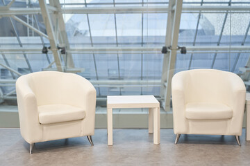 Two white armchairs with a coffee table on the background of the window. A place to copy an empty window template. Classic upholstered armchair by the window in the room. High quality photo