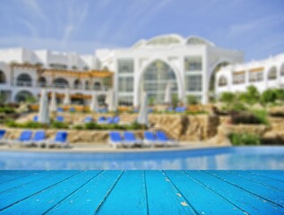 Empty table top and blurred swimming pool in tropical resort in summer for display or montage your products.