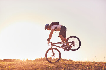 A cyclist riding a bike on a mountain at sunset