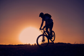 A cyclist riding a bike on a mountain at sunset