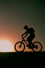 Obraz na płótnie Canvas A cyclist riding a bike on a mountain at sunset