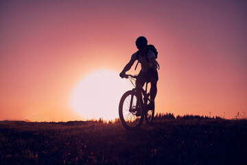 Obraz premium A cyclist riding a bike on a mountain at sunset