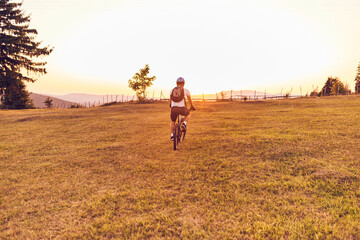Fototapeta na wymiar A cyclist rides a bike on forest roads at sunset